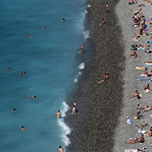 Tourists sunbathe and swim at the beach during a sunny summer day in Nice, southeastern