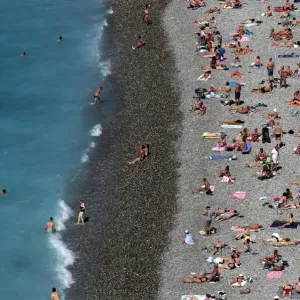 Tourists sunbathe and swim at the beach during a sunny summer day in Nice, southeastern Tourists sunbathe and swim at the beach during a sunny summer day in Nice, southeastern