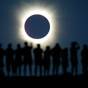 Tourists watch the sun being blocked by the moon during a solar eclipse in the Australian outback