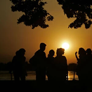 Tourists watch sun sets over Kashmirs Dal Lake in Srinagar