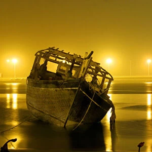 A traditional fishing boat lies at the sea-shore due to bad weather and low-tides