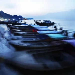 Traditional Thai fishing boats are swayed by small waves as they are anchored on a