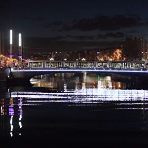 A tram crosses a bridge over the river Liffey at night in Dublin
