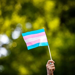 Transgender rights activist waves a transgender flag as they protest the killings of