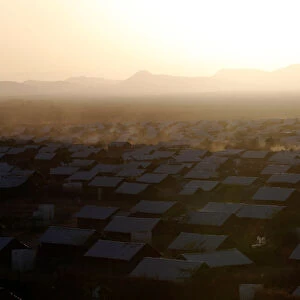 A vehicle drives at dusk within recently constructed houses at the Kakuma refugee camp in