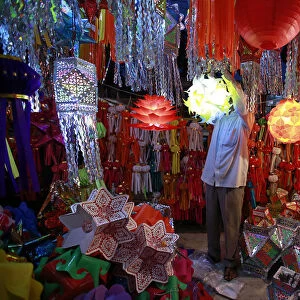 A vendor hangs a lantern for sale at a Diwali market in Mumbai