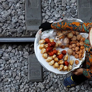 A vendor sells cakes for tourists along a railway in Hanoi