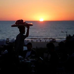 A vendor sells candied apples during the sunset on the beach in Gaza City