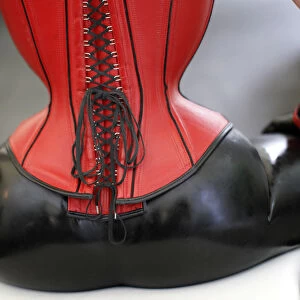 A visitor wearing a latex outfit and leather corset pauses at the rubber