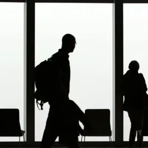 Visitors is silhouetted against a cloudy sky on the observation deck of a skyscraper