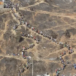 Volunteers form a line as they pass down debris from burned houses after a fire burned Volunteers form a line as they pass down debris from burned houses after a fire burned
