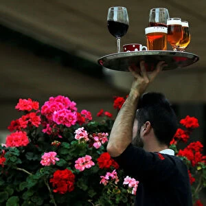 A waiter carries a tray with drinks at the terrace of a restaurant in downtown Malaga