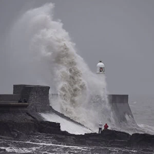 Waves crash over the lighthouse at Porthcawl, Wales