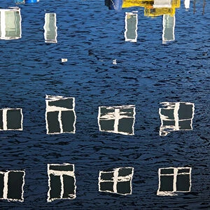 Windows take on different shapes as they reflect upon the water along a wharf in Portland