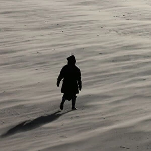 A woman braves the wind as she walks along New Brighton beach