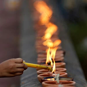 A woman burns a candle at a pagoda during Vesak Bochea Day on the outskirts of Phnom Penh