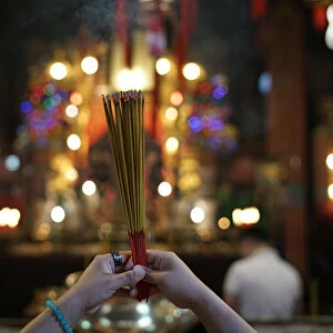 A woman burns incense as she prays at Man Mo Temple in Hong Kong