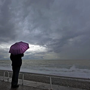A woman protects herself under an umbrella during an autumn day on the Promenade Des