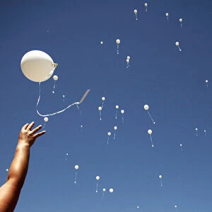 A woman releases a balloon into the air during the 20th anniversary of the closure