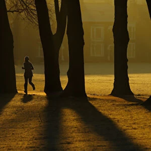 A woman runs through Victoria Park at sunrise in Leicester