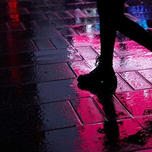 A woman is seen walking through a rain soaked sidewalk at Times Square in New York