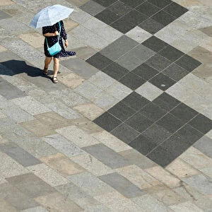 A woman shield herself from the sun with an umbrella on a hot summer day in Cologne