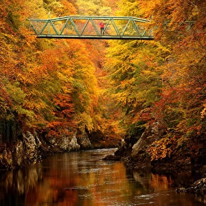 A woman stands on the footbridge over the river Garry near Pitlochry, Scotland