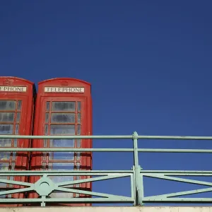 A woman stands next to two traditional telephone boxes in Brighton A woman stands next to two traditional telephone boxes in Brighton