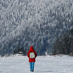 Woman takes a walk over the frozen up lake Eibsee in Grainau near Garmisch-Partenkirchen