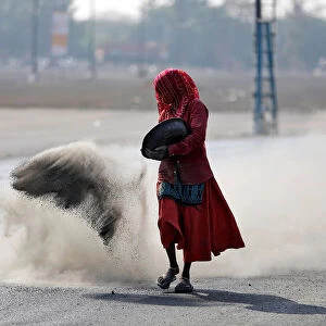 A woman throws a mixture of black ash, cement, concrete powder