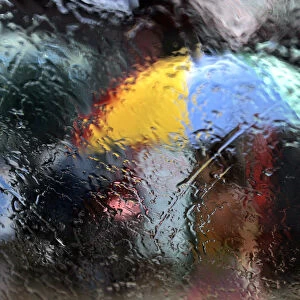 A woman walking with an umbrella is seen from a window as it rains during the monsoon