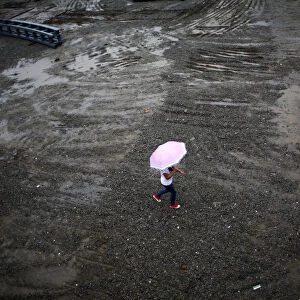 A woman walks at a construction site on a rainy day at the financial district of Pudong