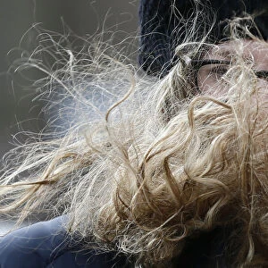 A womans hair is blown across her face as she crosses the Millennium Bridge during