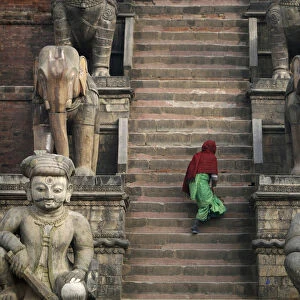 A women climbs the stairs to a temple in Bhaktapur
