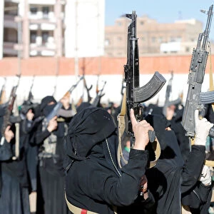 Women loyal to the Houthi movement hold up rifles as they attend a gathering to show