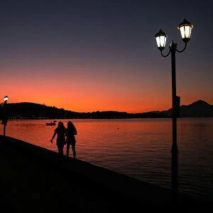 Two women walk by the sea during sunrise in Raches village
