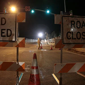 A worker places traffic cones on the road as the Mulholland bridge is closed over the 405