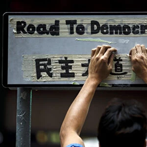 A worker removes masking tape left on road sign by pro-democracy protesters during