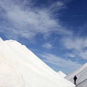 A worker walks in between mounds of sea salt in a farm near the town of Ses Salines