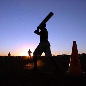 Youngsters play cricket using traffic cones as wickets in the twilight in Soweto township
