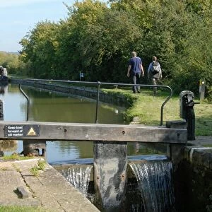Canal lockgate and towpath with walkers, Aylesbury Arm, Grand Union Canal, near Puttenham, Hertfordshire, England