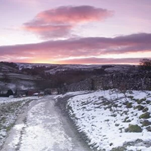 View of gate, drystone walls, footpath and surrounding hillside in snow at sunrise, Malham Cove, Malhamdale