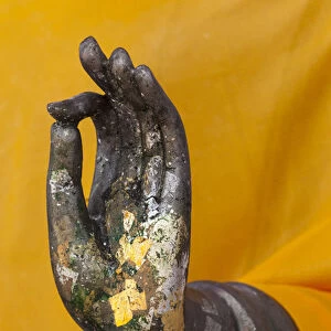 Thailand. Buddha Statue hand with gold leaf tokens