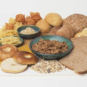 Assorted breads, whole and sliced, breakfast cereal, cooked rice and pasta in bowls, uncooked pasta and plain bagel
