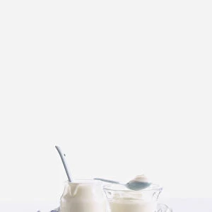 Plain white yoghurt in glass jar and glass bowl, with spoons
