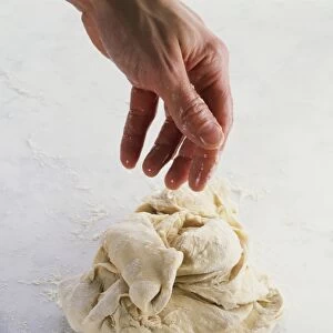 Wet hand over bread dough ball, close-up