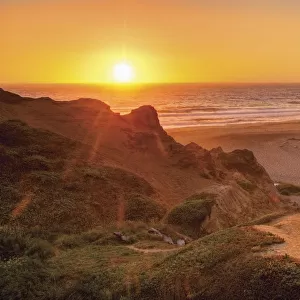 Orange california sunset on the ocean with trail down to a beach