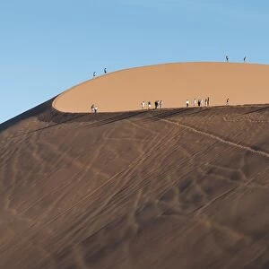 Tourists walking on the top of the famous Dune 45 sand dune. Sossuvlei, Namibia