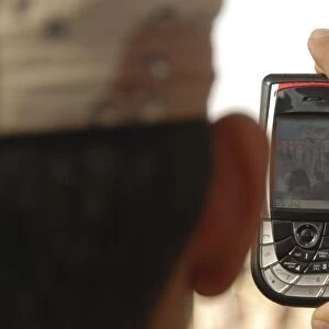 An Iraqi soldier records a change of command ceremony with his cell phone