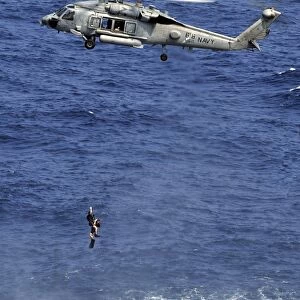 Search and rescue swimmers being hoisted into a helicopter